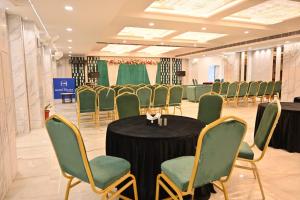 a conference room with a black table and green chairs at Hotel Velvet The Ultimate in Prayagraj