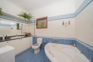 a bathroom with a tub and a toilet and a sink at Theros Maisonette by A&D Properties in Porto Rafti