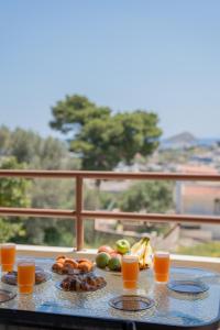 a table with fruits and oranges and glasses of orange juice at Theros Maisonette by A&D Properties in Porto Rafti +29 photos