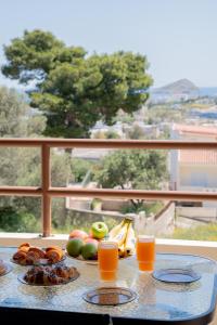 a table with fruit and orange juice on a balcony at Theros Maisonette by A&D Properties in Porto Rafti