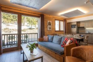 a living room with a couch and a kitchen at Residence Le Roc Noir by Alpapart in La Rosière