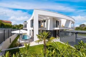 a white house with a curved roof with a swimming pool at Villa Sarah in Vantačići