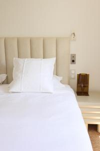 a bed with white sheets and pillows in a room at Hôtel Casa Elena in Erbalunga