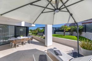 an umbrella on a patio with a table and chairs at Villa Sarah in Vantačići +42 photos