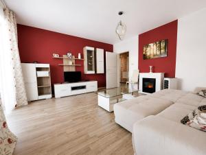 a living room with a white couch and a red wall at Brasov Altipiani Apartments in Braşov