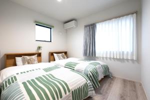 two beds in a bedroom with a window at HOTEL StayLuck KOTOHIRA - 琴平駅徒歩4分 in Kotohira