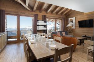a dining room with a table and chairs and a couch at Residence Le Roc Noir by Alpapart in La Rosière