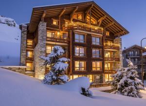 a log home in the snow with trees in front at Résidence Almes 1 et Almes 2 by Alpapart in Tignes