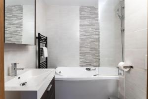 a white bathroom with a tub and a sink at Résidence Almes 1 et Almes 2 by Alpapart in Tignes +15 photos