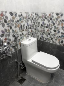 a white toilet in a bathroom with a mosaic wall at Sai Meridian in Pondicherry +16 photos