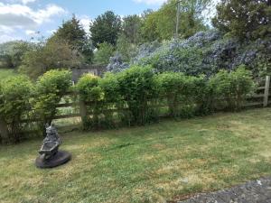 a garden with a fence and a statue in the grass at Elderflower Cottage in Stamford +4 photos