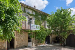 an old stone building with a sign for a club inn at Gîtes du Parc in Vallon-Pont-dʼArc