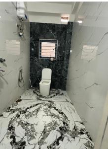 a bathroom with a toilet in a room with marble walls at SS Hostel Siliguri in Siliguri +5 photos