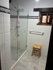 a bathroom with a glass shower with a wooden stool at rincón de covadonga in Caño