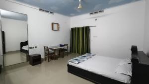 a bedroom with a bed and a table and a desk at LlBRA REGENCY in Guruvāyūr