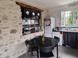 a kitchen with a black table and a refrigerator at Gîtelabaronnaise avec piscine chauffée prés parc Asterix in Baron