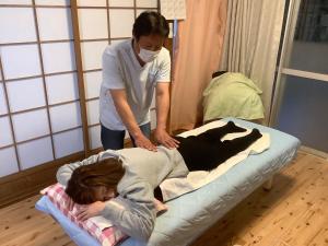 a woman is laying on a hospital bed with a nurse at ゲストハウスめぐみ in Iizuka
