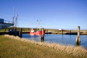 a red boat is docked in a body of water at Süderhafen 2c in Nordstrand