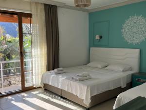 a bedroom with a bed with blue walls and a window at Melinda Pension & Restaurant in Mesudiye