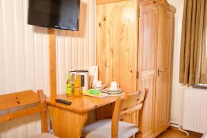 a room with a wooden table with a television on it at Seetuun-Hoff - Studio in Nordstrand +3 photos