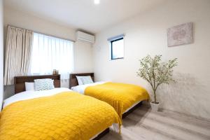 two beds in a room with yellow blankets at HOTEL StayLuck KOTOHIRA - 琴平駅徒歩4分 in Kotohira