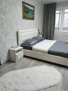 a bedroom with a large bed and a white rug at Строитель 39 in Oral