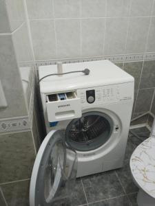 a washing machine in a bathroom next to a toilet at Строитель 39 in Oral