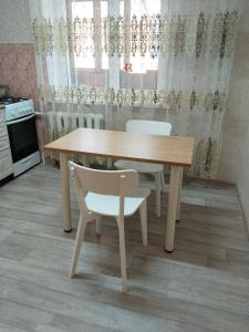 a wooden table and two white chairs in a kitchen at Строитель 39 in Oral +10 photos