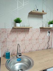 a sink in a kitchen with pink tiles at Строитель 39 in Oral