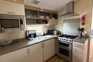 a small kitchen with a stove and a sink at Seaside Lodge Haven in St Osyth in Jaywick Sands
