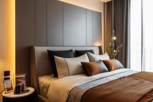 a bedroom with a large bed with brown and white pillows at The Panora Estuaria Pattaya in Na Jomtien