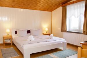 a bedroom with a white bed with two stuffed animals on it at Seetuun-Hoff - Dree in Nordstrand