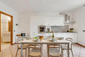 a white kitchen with a table and chairs at Juliette House: Shared Pool & Relax - Happy Rentals in Salò