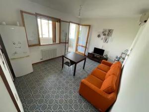 a living room with an orange couch and a table at Casa Ariel in Lido Adriano