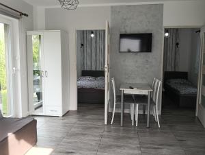 a dining room with a table and a bedroom at Domki pod Katalpami in Mikołajki