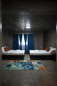a room with two beds with blue curtains and a rug at yolked suites in General Luna