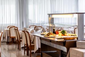 a dining room with a table with plates of food at Hotel Oasi Verde in Lido di Jesolo