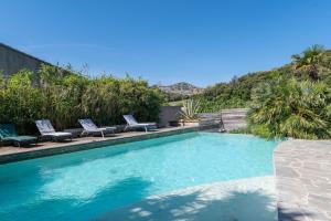 a swimming pool with lounge chairs next to a house at Le Studio - Ancienne Cave in Patrimonio