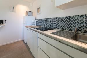 a white kitchen with a sink and a refrigerator at Le Refuge in Patrimonio