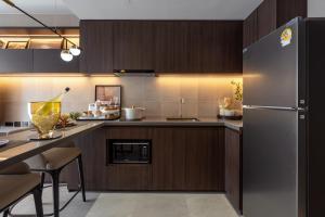 a kitchen with wooden cabinets and a refrigerator at The Panora Estuaria Pattaya in Na Jomtien +48 photos
