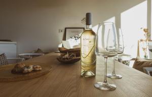 a bottle of wine and two wine glasses on a table at Bentu Boutique Apartment in San Nicolò Gerrei