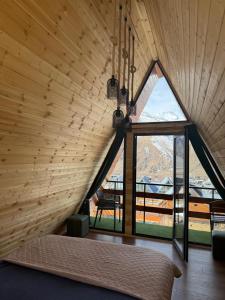 a bedroom with a large window in a wooden house at Cozy Home Kazbegi in Kazbegi