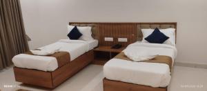 a room with two beds and a table with a chair at hotel ananth inn in Mahālingpur