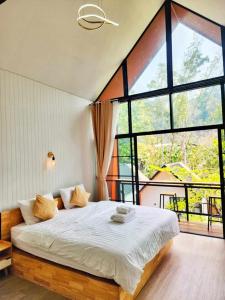 a bedroom with a large bed with a large window at Chertarn Homestay in Ban Pang Bo Hu Bon