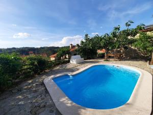 a large blue swimming pool in front of a house at Dão country house in Silgueiros