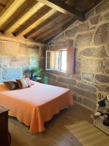 a bedroom with a bed in a stone wall at Dão country house in Silgueiros