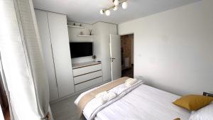 a white bedroom with a bed and a tv at Apartament Benicarlo2 in Brad