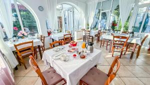 a restaurant with white tables and chairs and windows at Bed & Breakfast Haus Lucija in Baška