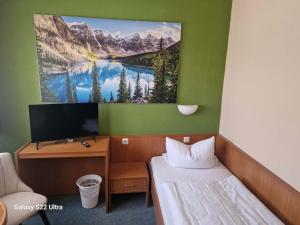 a room with a bed and a desk with a tv at Hotel Restaurant Yiamas in Breitenworbis