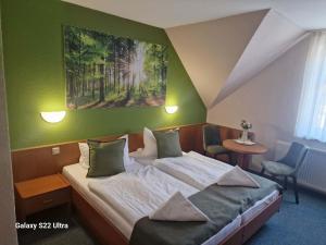 a bedroom with a bed and a painting on the wall at Hotel Restaurant Yiamas in Breitenworbis